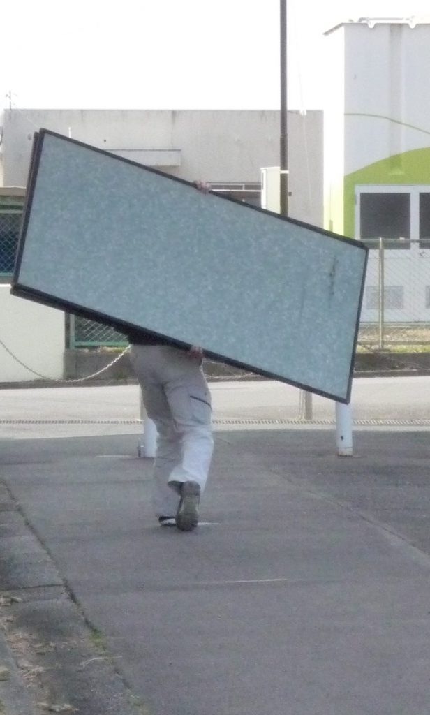 ふすまを運んでいる職人風にあおられる